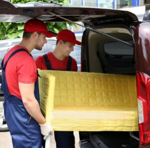 Sofa verladen Umzugshelfer laden ein gelbes Sofa in einen Transporter