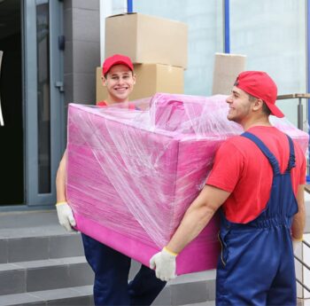 Umzug in Kaiserslautern Zwei Umzugshelfer tragen ein in Folie gepacktes Möbelstück – Umzug in Kaiserslautern