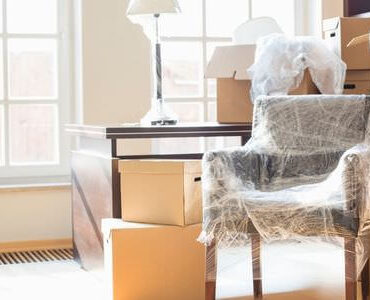 Kartons zwischen Sesseln in einem hellen Zimmer – Umzugskartons Kaiserslautern